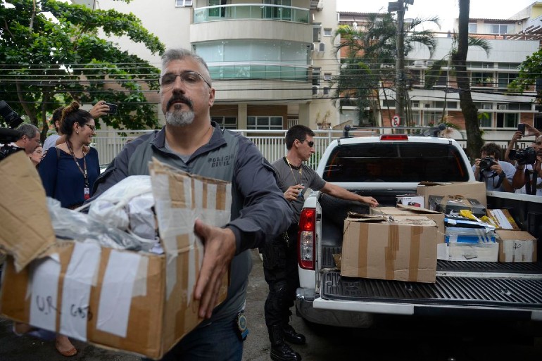 Policiais carregam caixas apreendidas em endereo ligado a suspeito de matar a vereadora