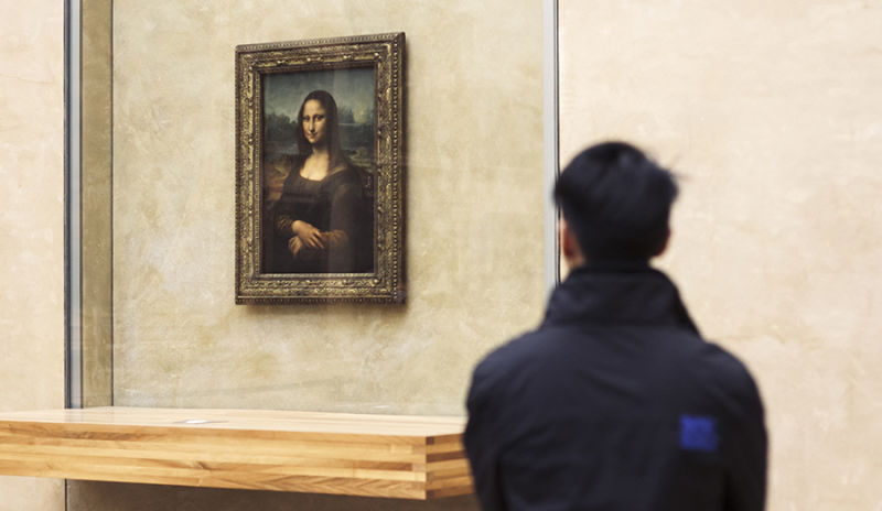 Turista no Museu do Louvre apreciando a obra Mona Lisa de Leonardo da Vinci