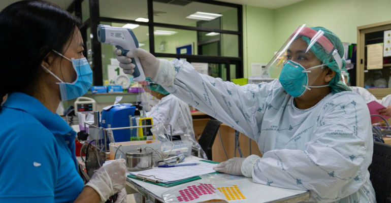 Profissional de sade verifica a temperatura de paciente em hospital na Tailndia